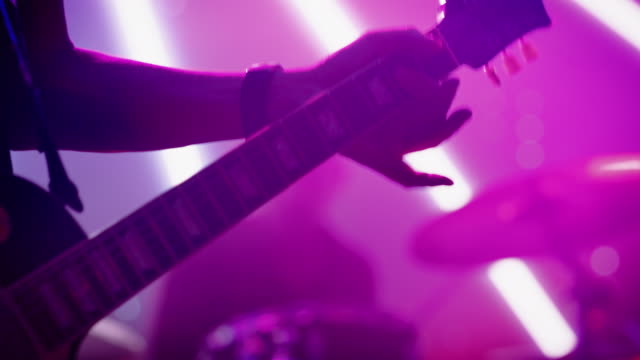 Rock Band Performing at a Concert in a Night Club. Close Up Shot of a Six String Guitar Played by a Musician. Live Music Party in Front of Bright Colorful Strobing Lights on Stage.