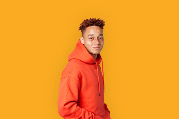 Young adult millennial standing on orange background
