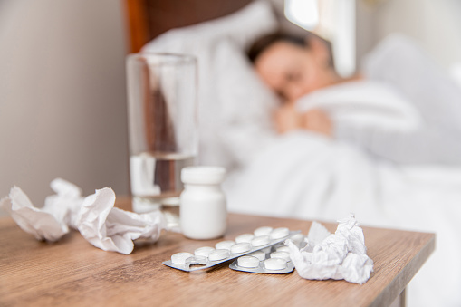 Focus on antidepressants of the nightstand of a depressed woman in bed - mental illness concepts