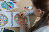 Close-up on a woman coloring mandalas at home