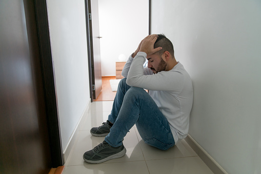 Frustrated Latin American man struggling with grief at home - mental illness concepts