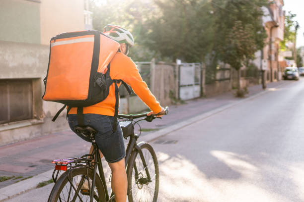 istock Male delivery guy riding bicycle with backpack trough the city 1270303636