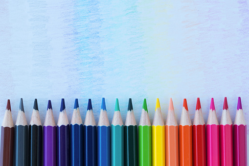 colored pencils lie in a horizontal  row like a rainbow. traces of these pencils are drawn on a white background. Creative idea. Back to school, purchasing school supplies. Education concept.