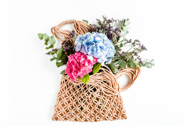 Beautiful bouquet of hydrangeas in a string, eco bag on white background. Flat lay, top view
