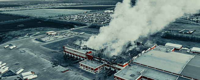 Aerial view of fire in burning industrial factory building with big smoke, copy space for text.