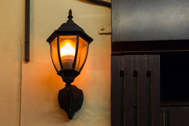 istock black iron lantern in retro style illuminates wall of building facade with warm glow light, closeup of lighting fixture, nobody. 1270315739