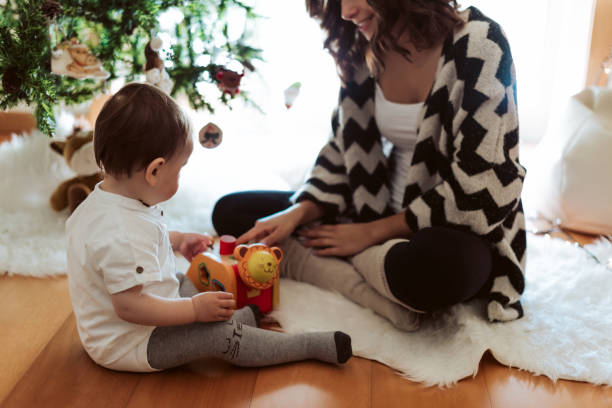 istock Mother and baby playing around the Christmas Tree 1270315938
