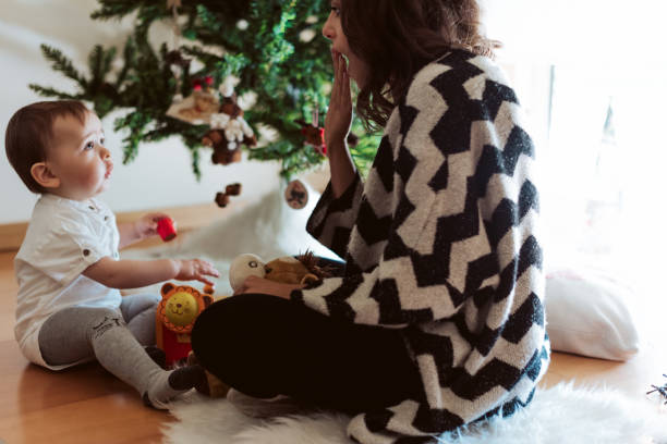 istock Mother and baby playing around the Christmas Tree 1270315940