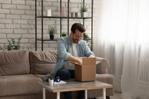 istock Happy young man unpack carton box with internet order 1270316245