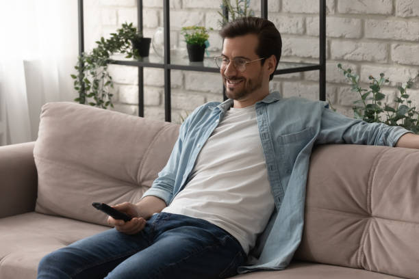 istock Smiling man relax on sofa watching TV 1270316253