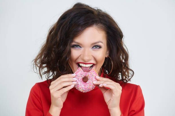 istock attractive girl in a red dress bites a doughnut 1270326700