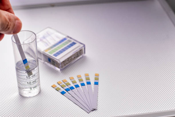 istock hand inserting a ph control strip into a graduated cylinder with water 1270327320