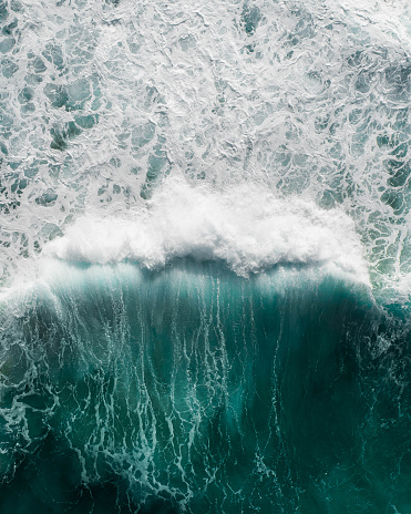 Beautiful aerial view of a wave crashing in a blue ocean during a storm