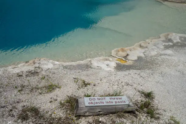 Photo of Yellowstone National Park - Sign reminding visitors not to throw objects into the pools. Sapphire Pool in photo