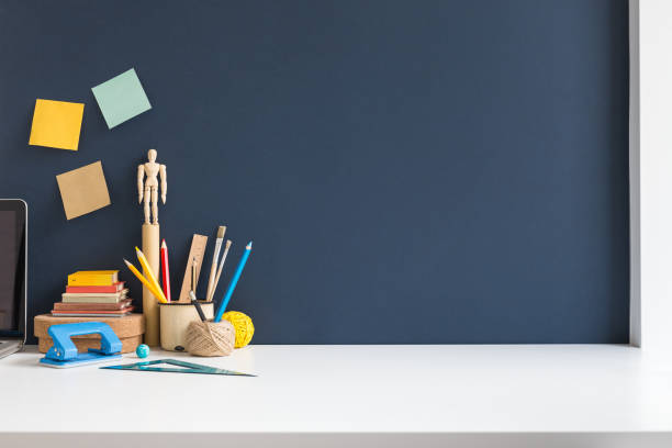 istock Workspace of a student with empty space on a desk. Mockup. dark blue wall. 1270334250