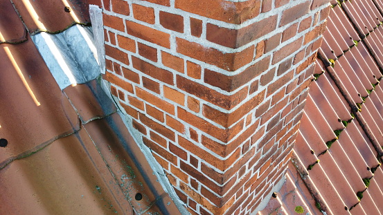 Stone chimney on red metal roof.