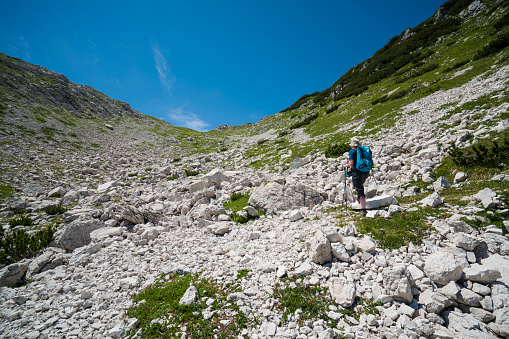 Back view of Senior woman hiking near Komna in Triglav national park,  Slovenia. It is hiking destination with mountain cabin near by.