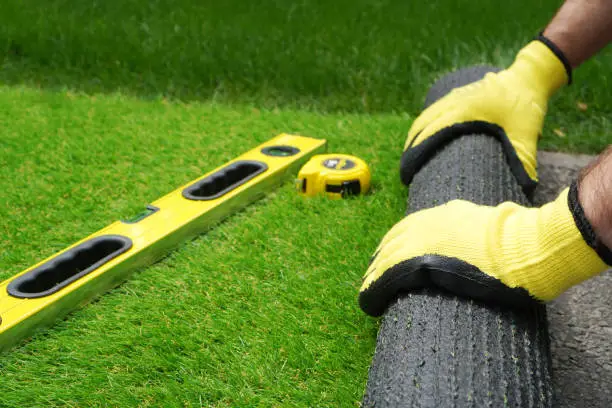 Photo of Man's hands spread an artificial turf roll
