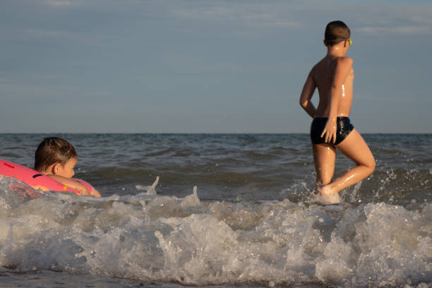два брата 5 и 10 лет плавают и веселиться в море в ясный солнечный день. - child head and shoulders elementary age front view стоковые фото и изображения
