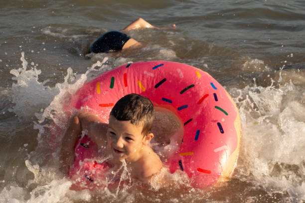два брата 5 и 10 лет плавают и веселиться в море в ясный солнечный день. - child head and shoulders elementary age front view стоковые фото и изображения