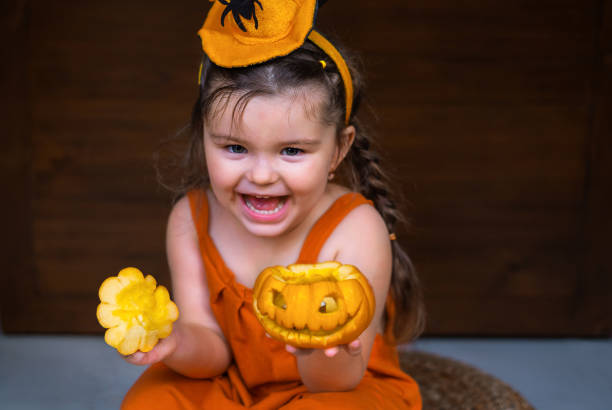 Happy child  holding Halloween decoration Jack-O-Lantern on the hands on a wooden background
