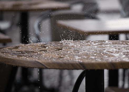 Heavy raindrops fall on the table in the city street restaurant.