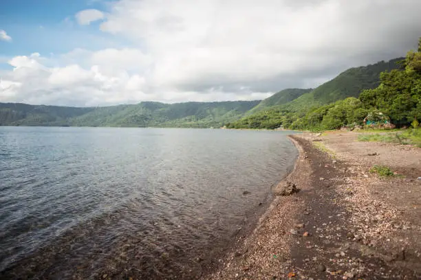 Photo of shore of Laguna de Apoyo lake in inactive volcano caldera surrounded by jungle