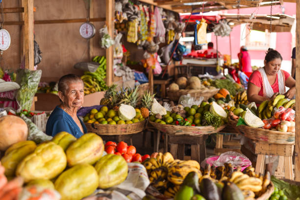 尼加拉瓜老婦人在市場攤位上被五顏六色的蔬菜和水果包圍。 - 尼加拉瓜 個照片及圖片檔