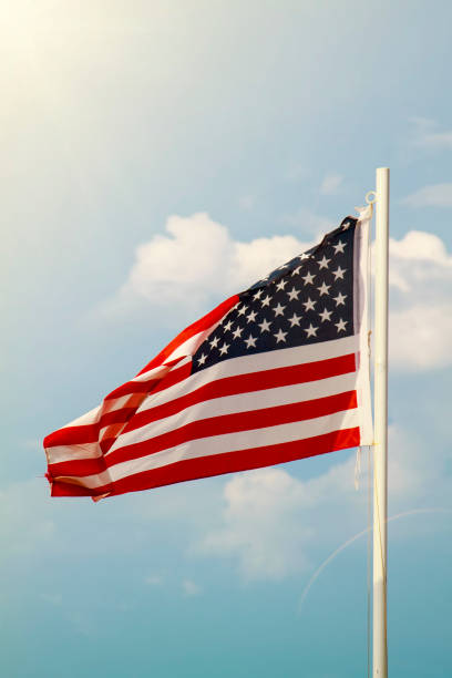istock American flag on a blue sky with clouds background 1270353588