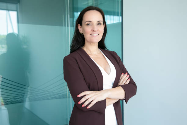 Happy successful black haired businesswoman Happy successful black haired businesswoman wearing formal suit, standing with arms folded and looking at camera and smiling. Medium shot, vertical. Business portrait concept medium shot stock pictures, royalty-free photos & images