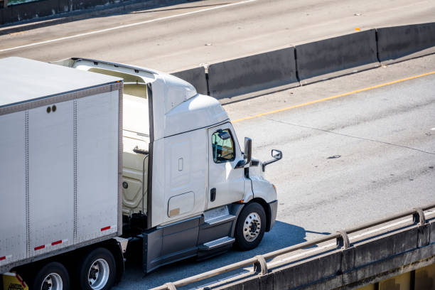 istock White big rig semi truck with low cab transporting cargo in dry van semi trailer running on the overpass highway intersection 1270363074