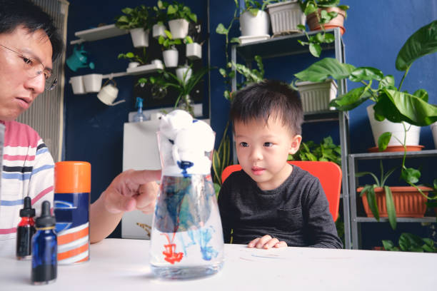 Parent sitting homeschooling with little kid, Father and son having fun making easy science experiment, Kid-friendly easy science experiments at home concept