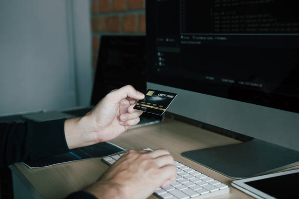 istock Hacker in the hood working with computer and holding credit card with payment hacking concept. 1270367556