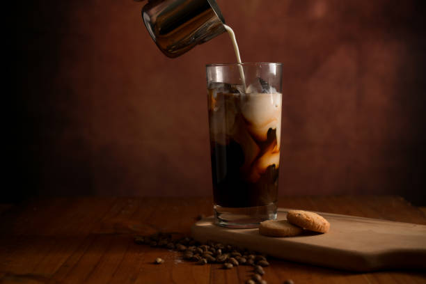 istock Glass of ice coffee while adding milk with biscuit and coffee beans on wooden table 1270368560