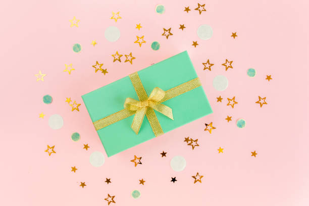 Gift or present box and stars confetti on a pink background. Colorful celebration, birthday. Christmas or New Year pattern. Flat lay, top view