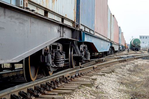 Freight cars with a wheelset node close-up going into the distance with the tanks of another train in the distance. Background.