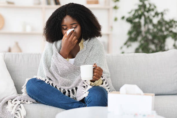 istock Sick afro girl wrapped in blanket drinking hot tea 1270373318