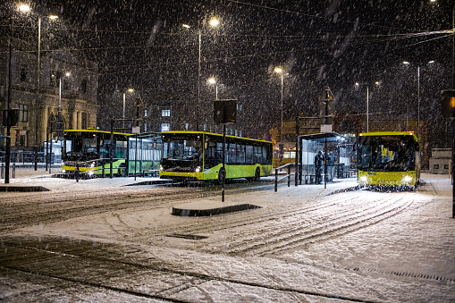 three buses at bus stop in front of reconstructed lviv railway station snowing winter night