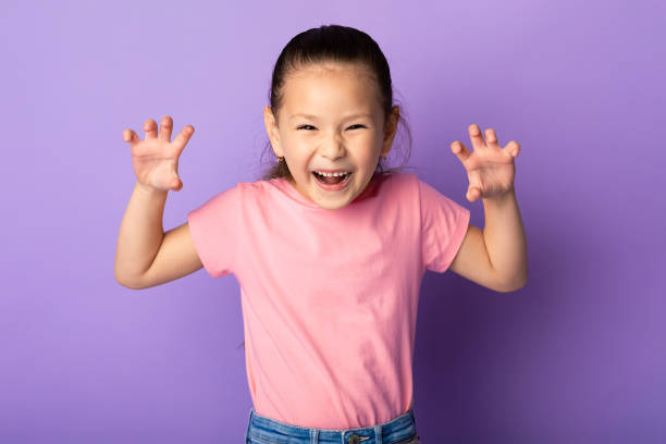 asiatische mädchen grimassieren und imitieren tiger, brüllen im studio - grimassieren stock-fotos und bilder