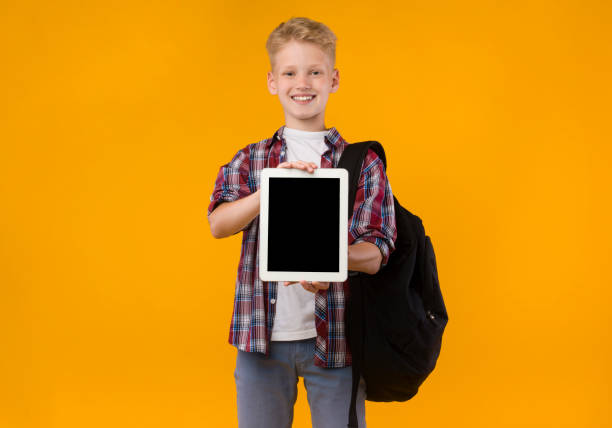istock Smiling school boy showing tablet screen at camera 1270374543