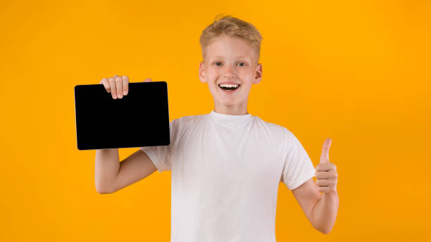istock Smiling school boy showing tablet screen and thumbs up 1270374551