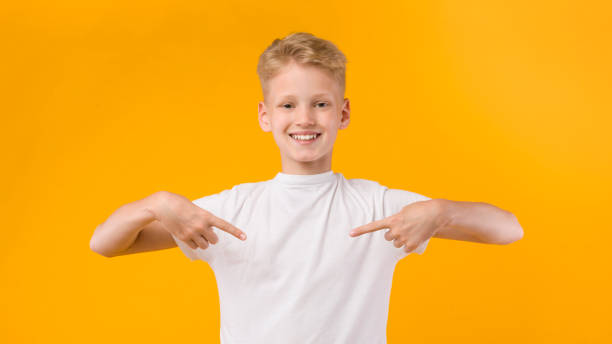 joven feliz señalando con los dedos a sí mismo - t shirt child white portrait fotografías e imágenes de stock