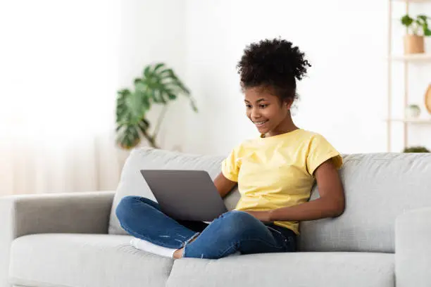 Photo of African Teen Girl Using Laptop Browsing Internet Sitting At Home