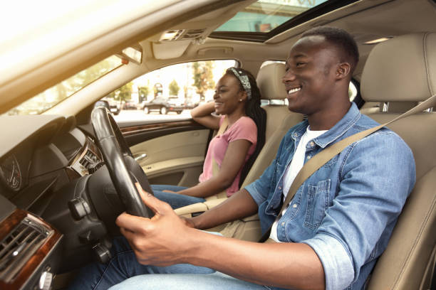 alegre pareja afroamericana en coche, vista lateral - conducir fotografías e imágenes de stock