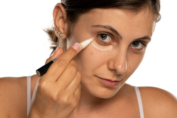 istock a young woman applies concealer under her eyes 1270375962