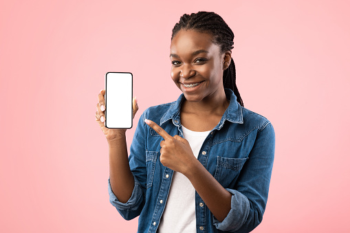 African American Woman Showing Cellphone Blank Screen Smiling To Camera Posing Over Pink Background. Studio Shot, Mockup