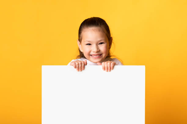 istock Asian kid hiding behind blank white advertising billboard 1270376730