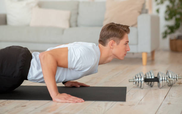 istock Morning workout. Handsome guy doing push-ups on mat in living room 1270376802