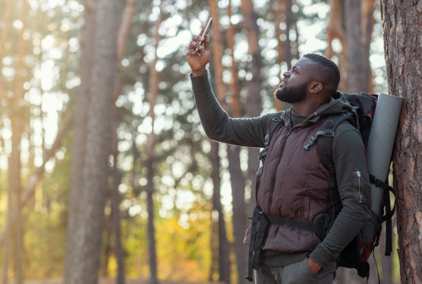 istock Black guy holding smartphone up, looking for gps in woods 1270376996