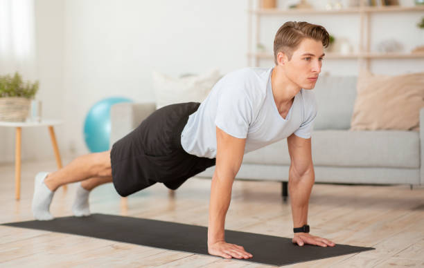 istock Stay at home, self-care during COVID-19 pandemic. Athletic guy doing plank 1270377049
